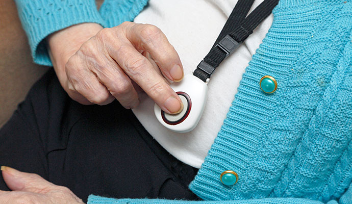 Senior person pressing a wearable emergency medical alert pendant button