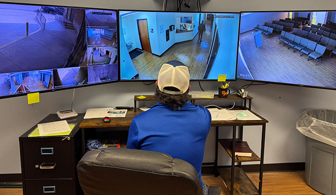 Security specialist monitoring live property surveillance camera feeds on multiple screens