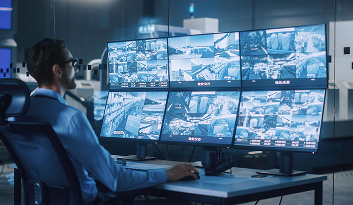 Security operator monitoring multiple surveillance camera screens in a monitoring center