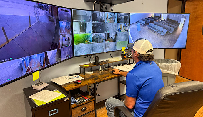 Security specialist monitoring commercial video surveillance feeds on multiple screens