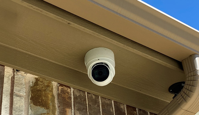 Outdoor security camera mounted under a residential roof eave