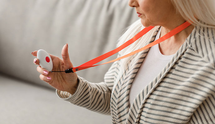 Senior woman holding an emergency medical alert pendant with lanyard
