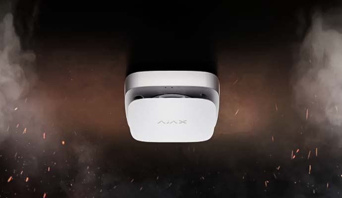 Smart smoke detector alarm installed on a ceiling detecting smoke and fire